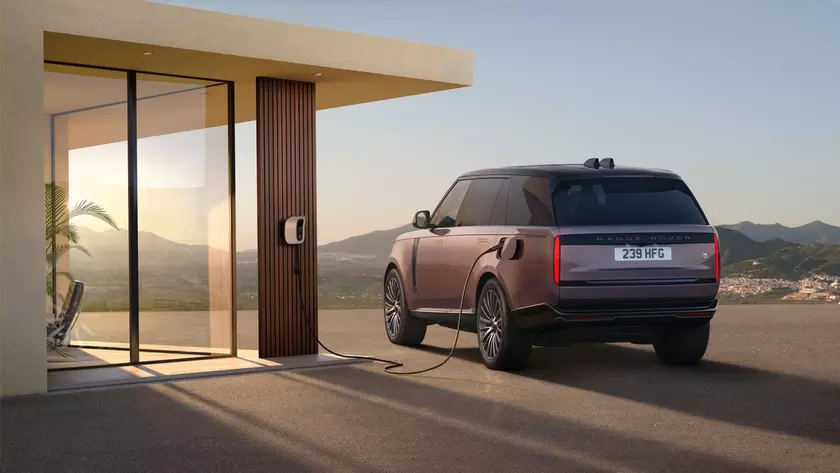 Range Rover заряжается у современного дома на закате солнца